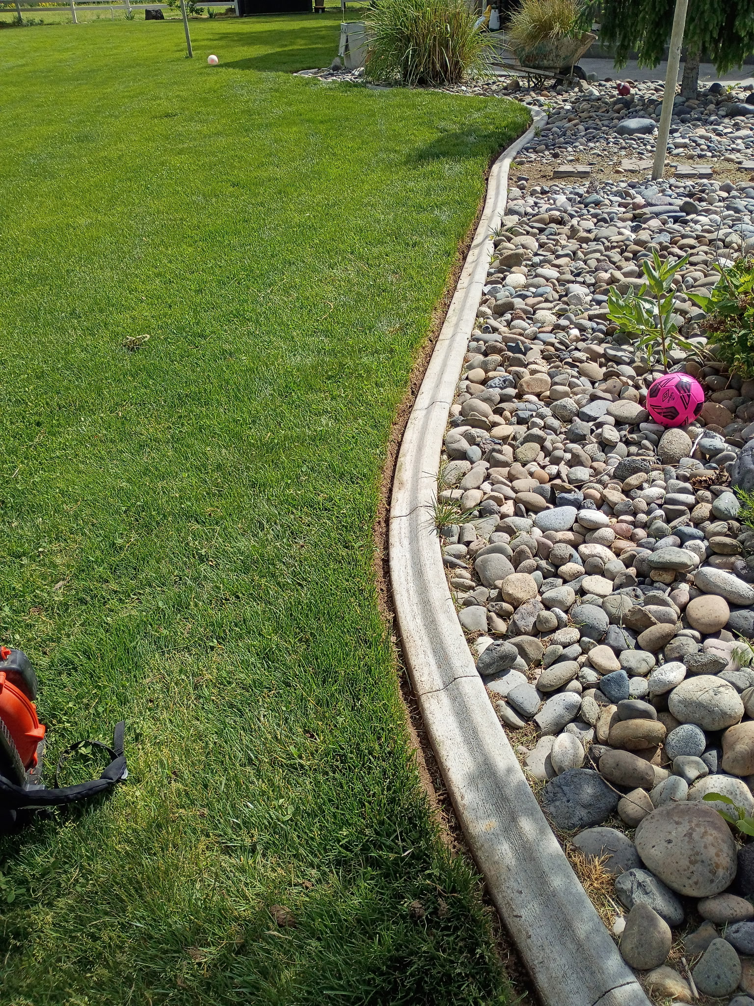 Clean concrete edging along a river rock bed